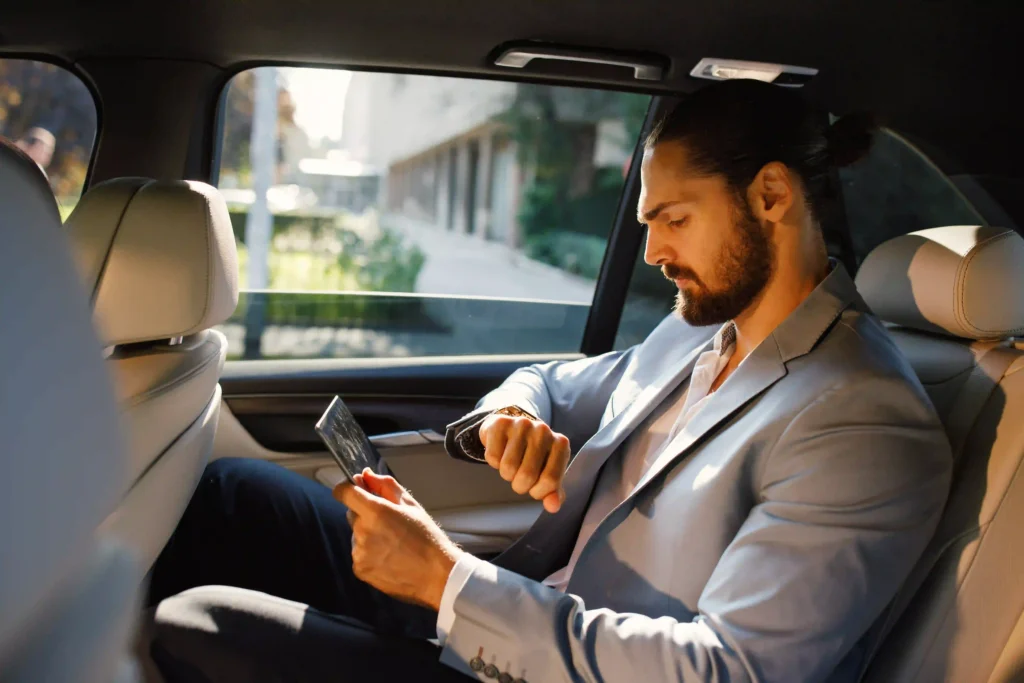 Businessman looking at the watch on the back of the limousine