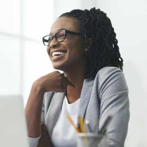 african-american-businesswoman-laughing-sitting-against-window-in-office-e1631573683612