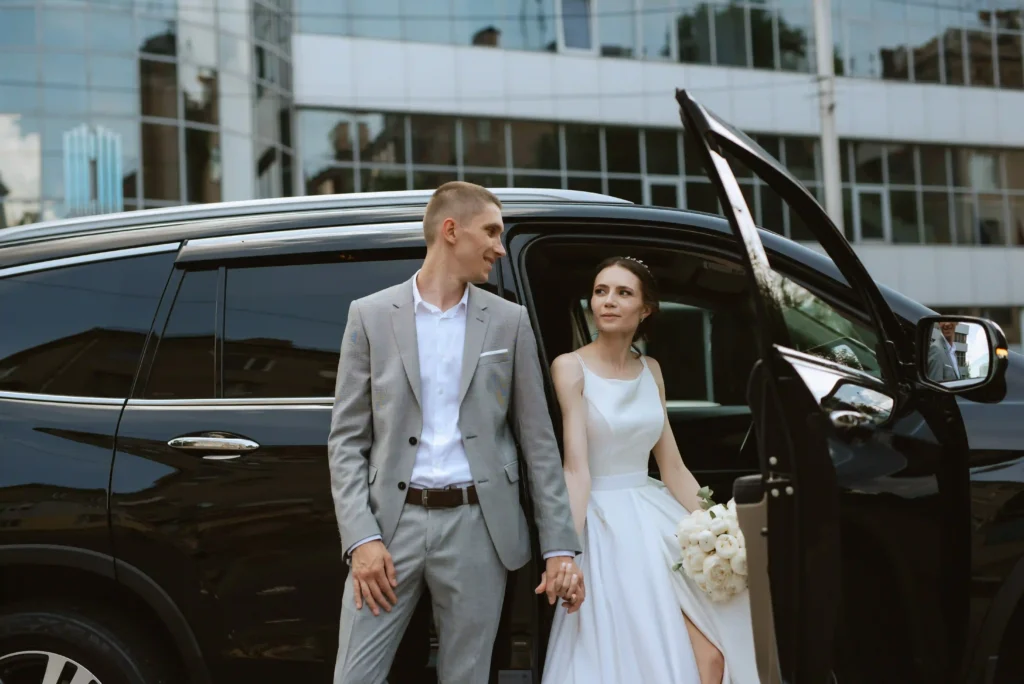 bride and groom with a black car