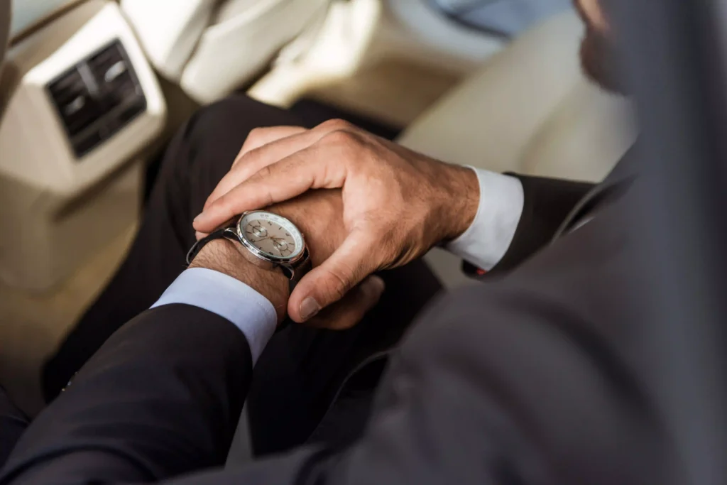 Businessman looking at the watch on the back of the limousine