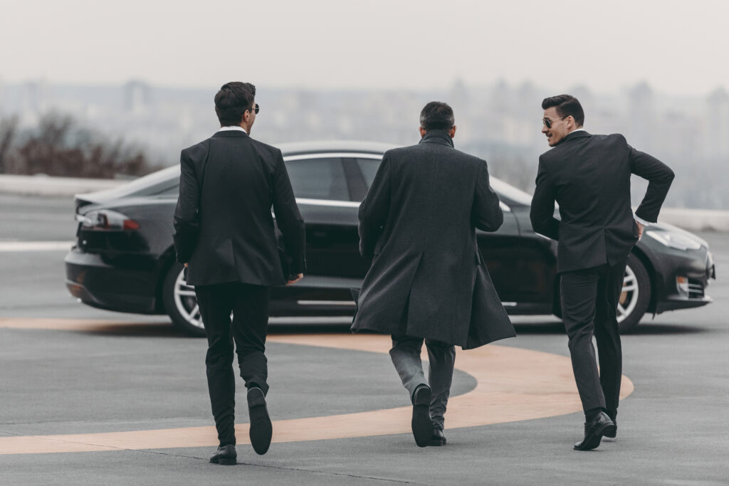 three businessman in airport with limo masters car